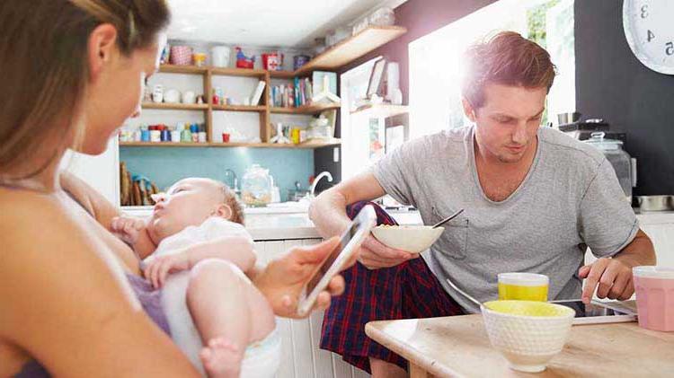 Young couple at a table with their baby and on their phones