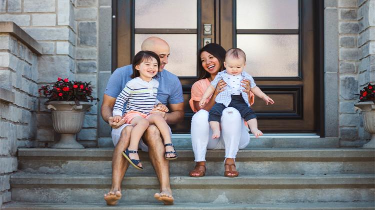 Young family sitting on their front porch steps.