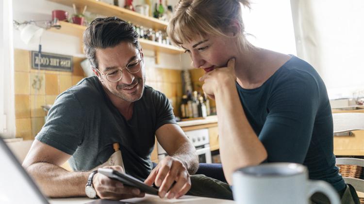 Couple sitting at a table in the kitchen using a smartphone.