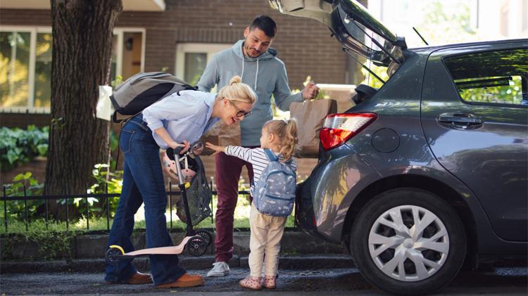 Happy family packing things in the back of the car.